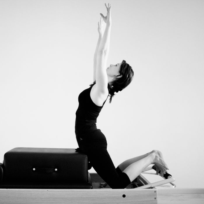 Pilates-oefening op de reformer, armen gestrekt (zwartwit)